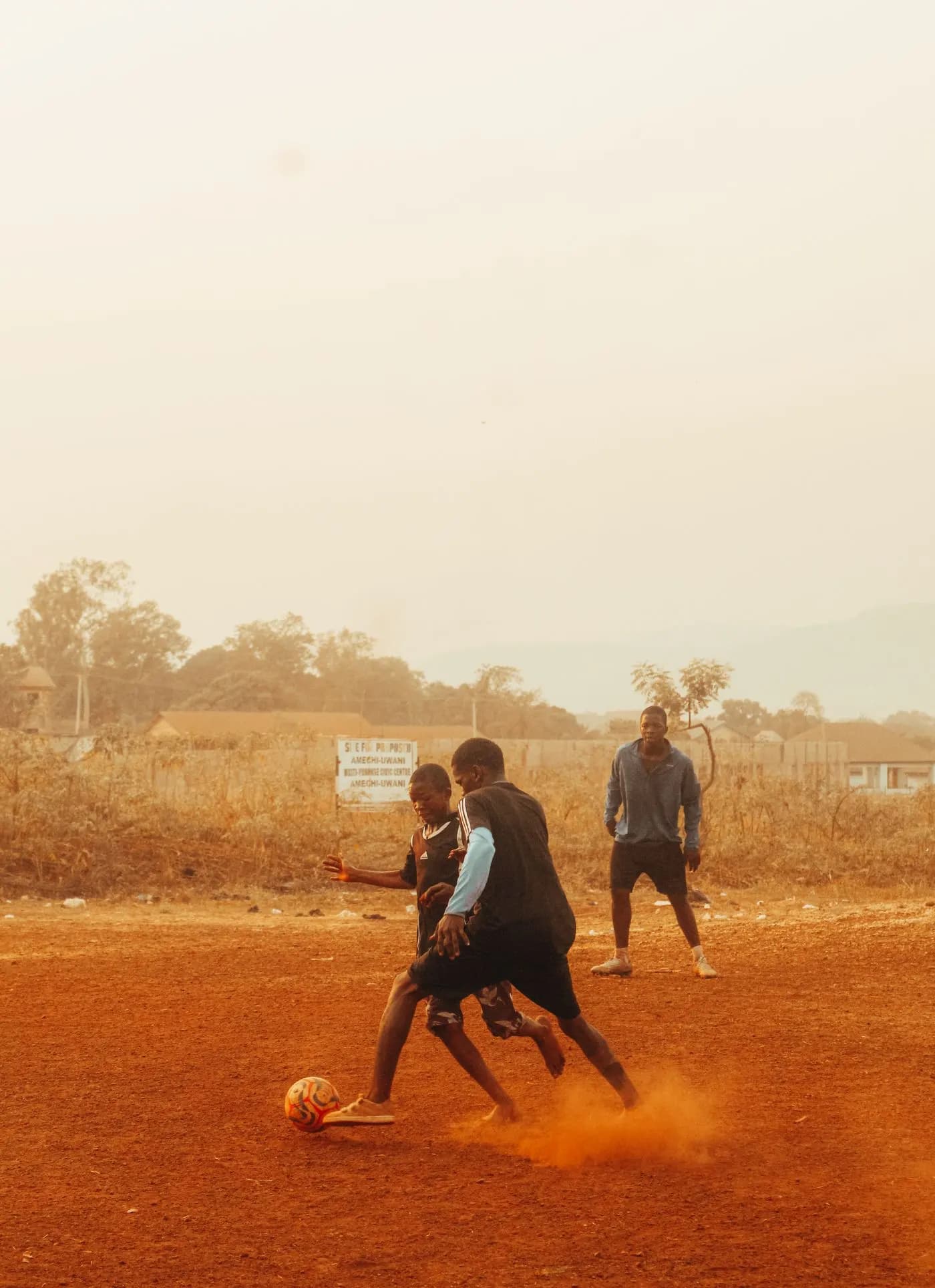 Duel entre deux joueurs sur un terrain de terre rouge, en fin de journée